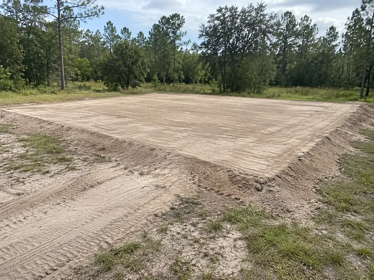 A level earth building pad with graded edges on a rural property.