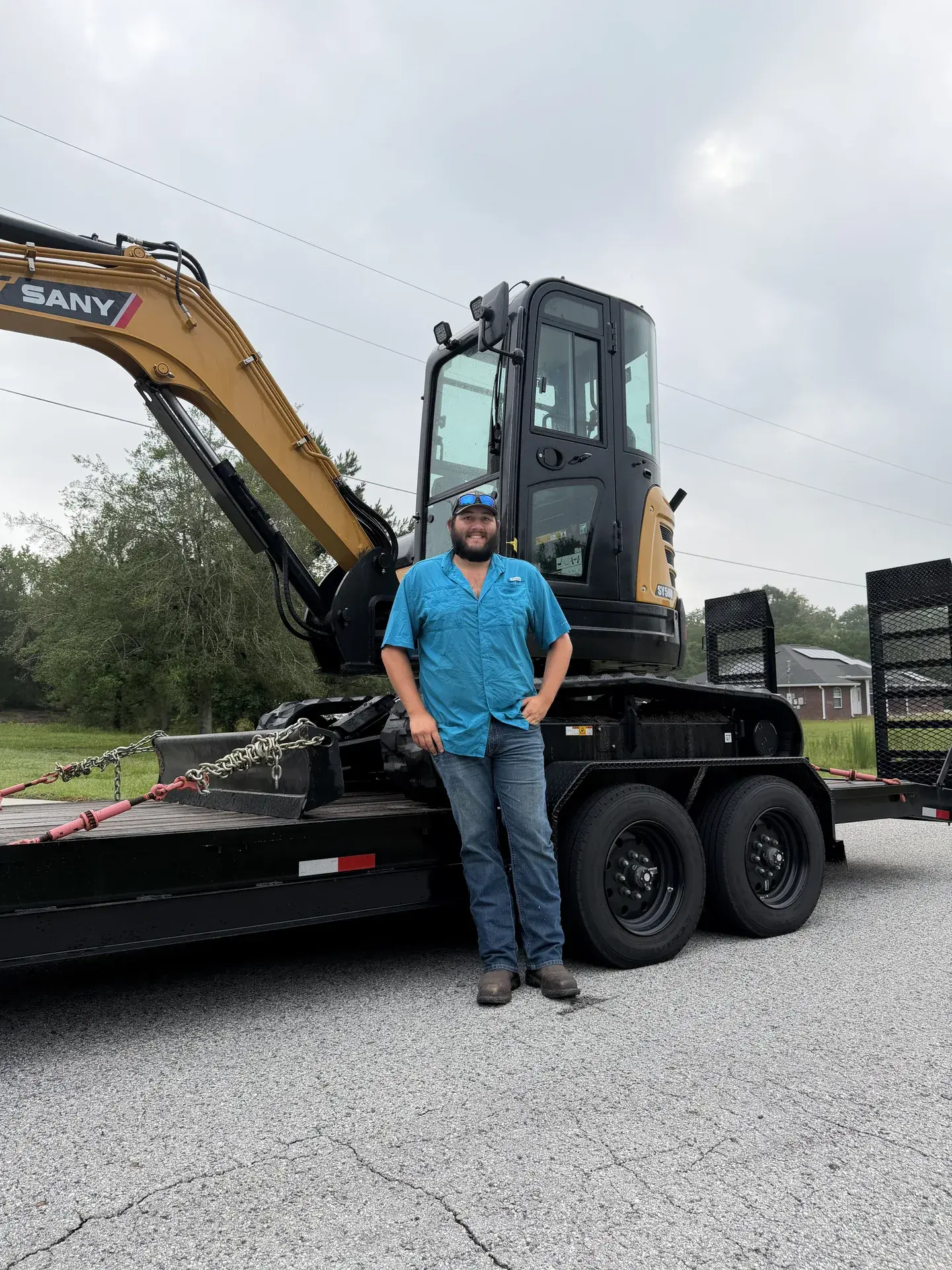 Zach Faller standing in front of Falcon Excavation equipment